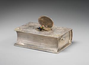 Maker unknown, mechanical singing bird box in book form, German, mid-20th century, silver, feathers. 12.3 x 8.3 x 4.1 cm. Gift of Lynn and Bruce Heckman, 2023 