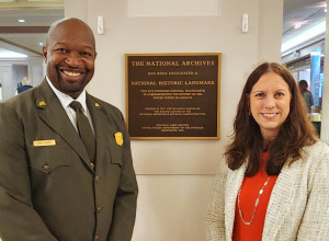 Archivist of the United States Dr. Colleen Shogan (right) and Brian Joyner, acting superintendent of Rock Creek Park (left), stand in front of the National Archives Building Historic Landmark plaque. 