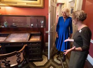 Her Majesty The Queen takes a look at Dicken's desk
