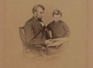 Original portrait photograph of Lincoln seated with a book and his son Tad, taken February 9, 1864