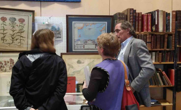 Two fairgoers talking with exhibitor William Hutchison, bookseller and ephemera specialist, based in Mendenhall, Pennsylvania