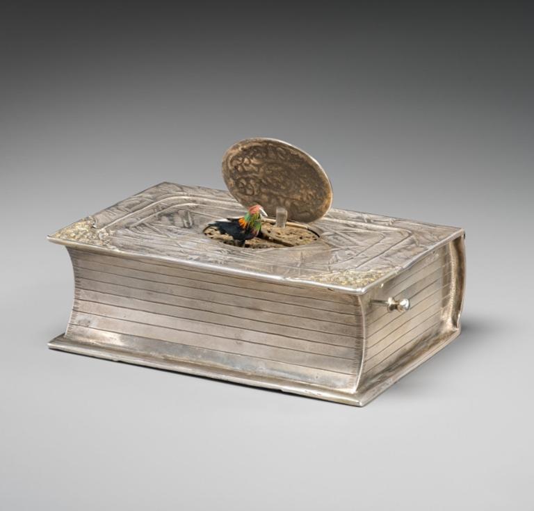 Maker unknown, mechanical singing bird box in book form, German, mid-20th century, silver, feathers. 12.3 x 8.3 x 4.1 cm. Gift of Lynn and Bruce Heckman, 2023